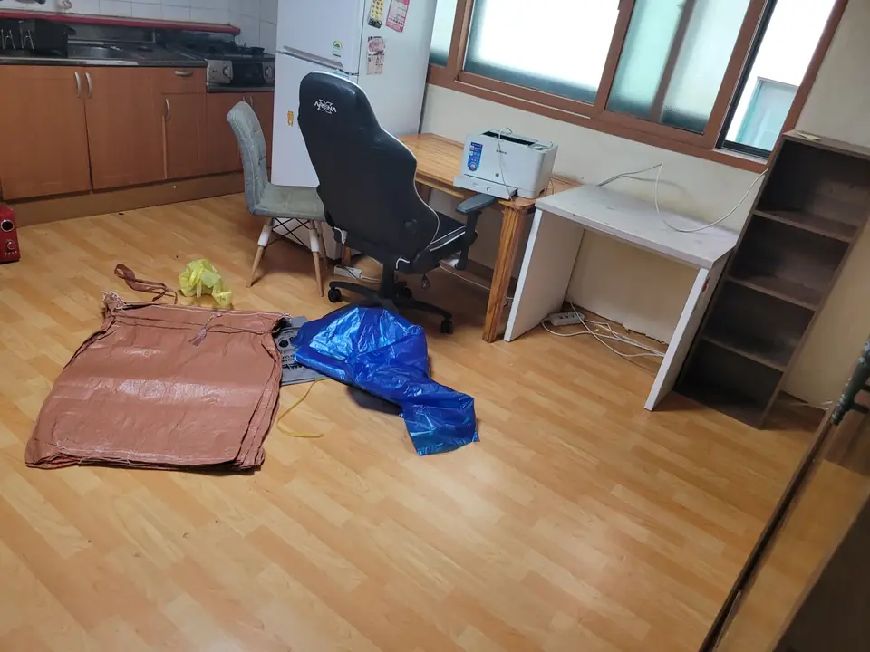바닥에 마대가 놓이고 책상과 의자가 있는 방