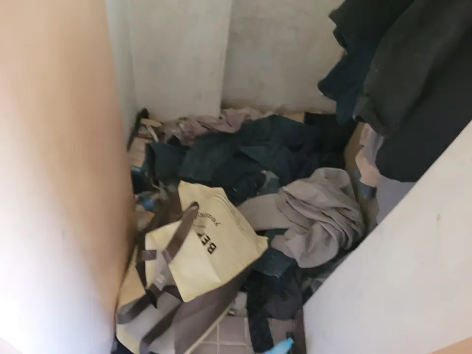 방 모퉁이에 옷가지와 상자가 쌓여 있는 모습