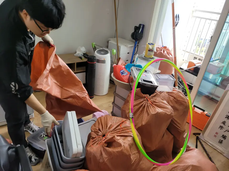 여러 작업자가 방 안 물품을 마대에 담고 있는 모습