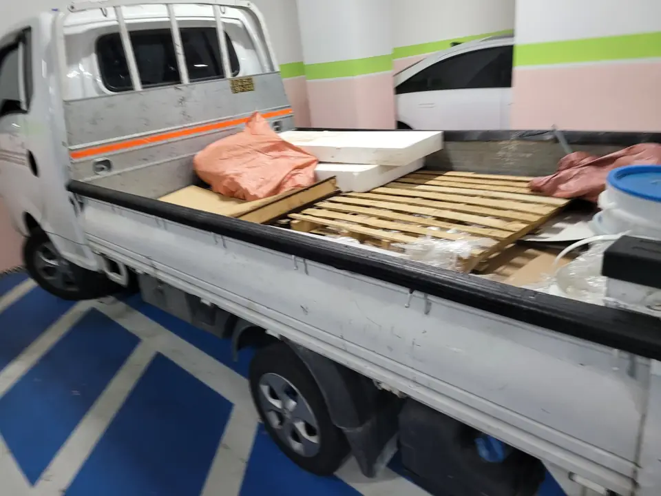 팔레트가 깔린 트럭 적재함에 자재와 마대가 실려 있는 모습
