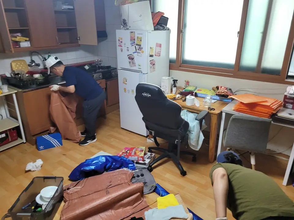 책상이 있는 방에서 작업자가 물품을 정리하는 모습